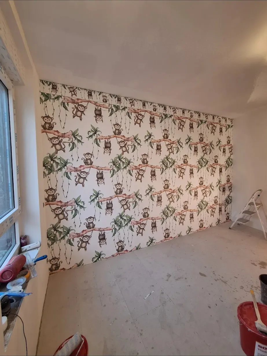 Kinderzimmerwand mit verspielter Affen-Mustertapete während der Verlegung